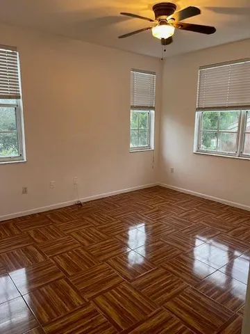 a view of empty room with wooden floor and fan