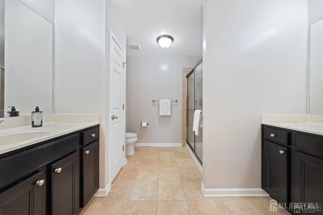 a spacious bathroom with a double vanity sink a toilet and a mirror