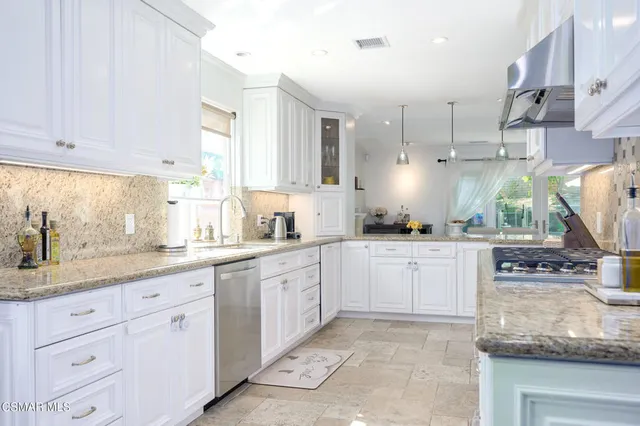 a kitchen with granite countertop white cabinets and stainless steel appliances