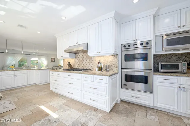 a kitchen with white cabinets and sink