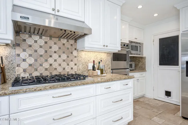 a kitchen with granite countertop white cabinets white appliances and sink