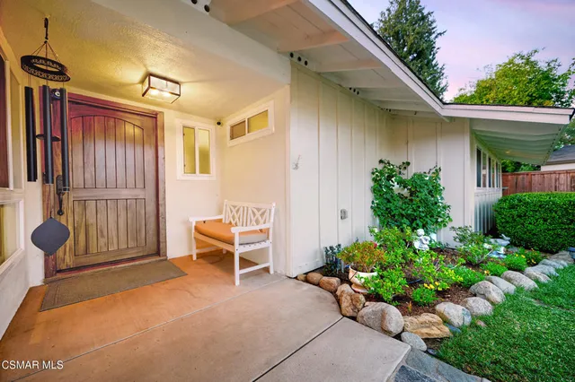 a front view of house with outdoor seating and potted plants