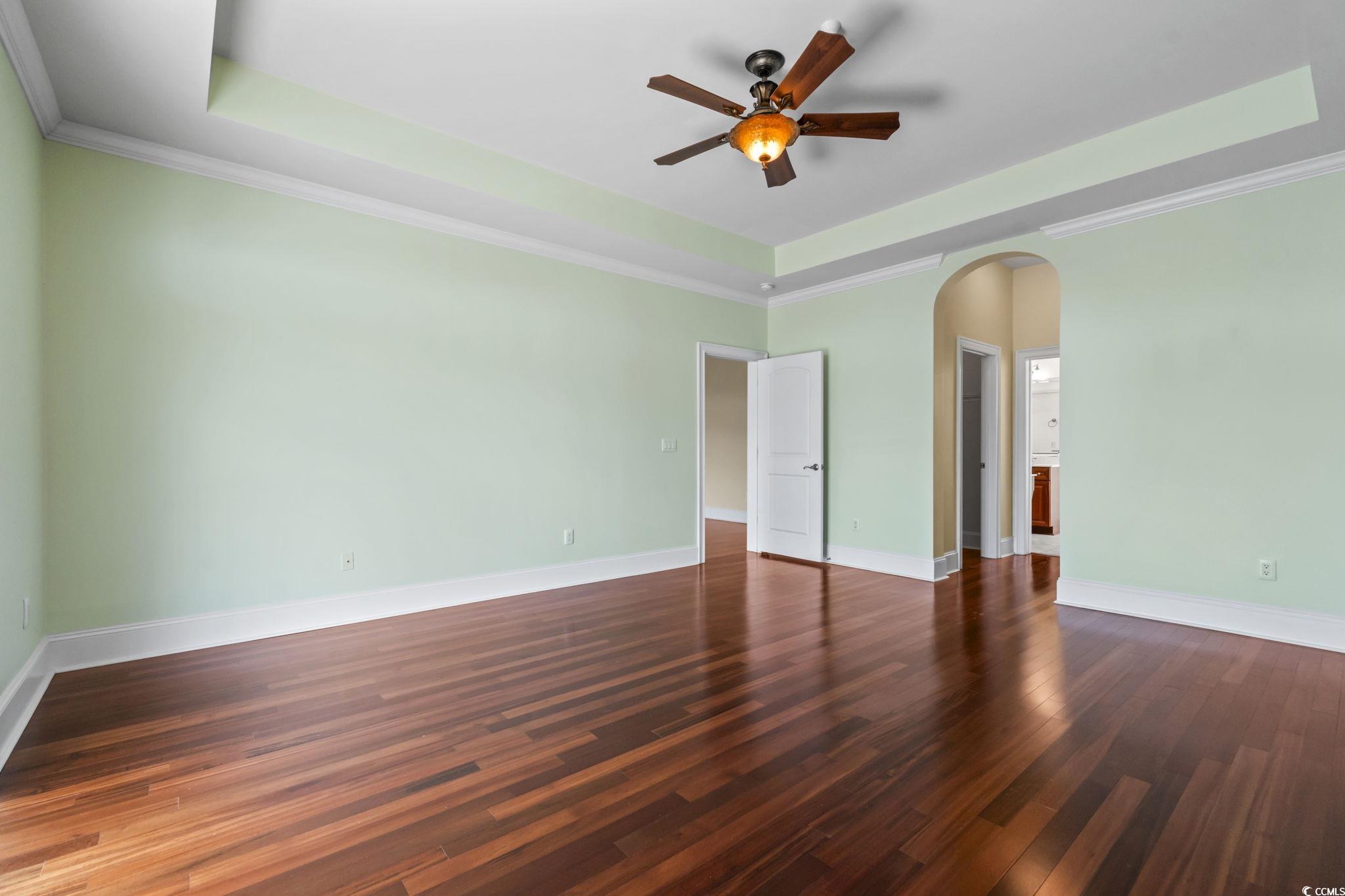249 Venice Way, Unit 3301 Myrtle Beach, SC 29577 - Photo 20 of 40 Unfurnished room featuring a tray ceiling, ornamental molding, dark wood finished floors, and arched walkways