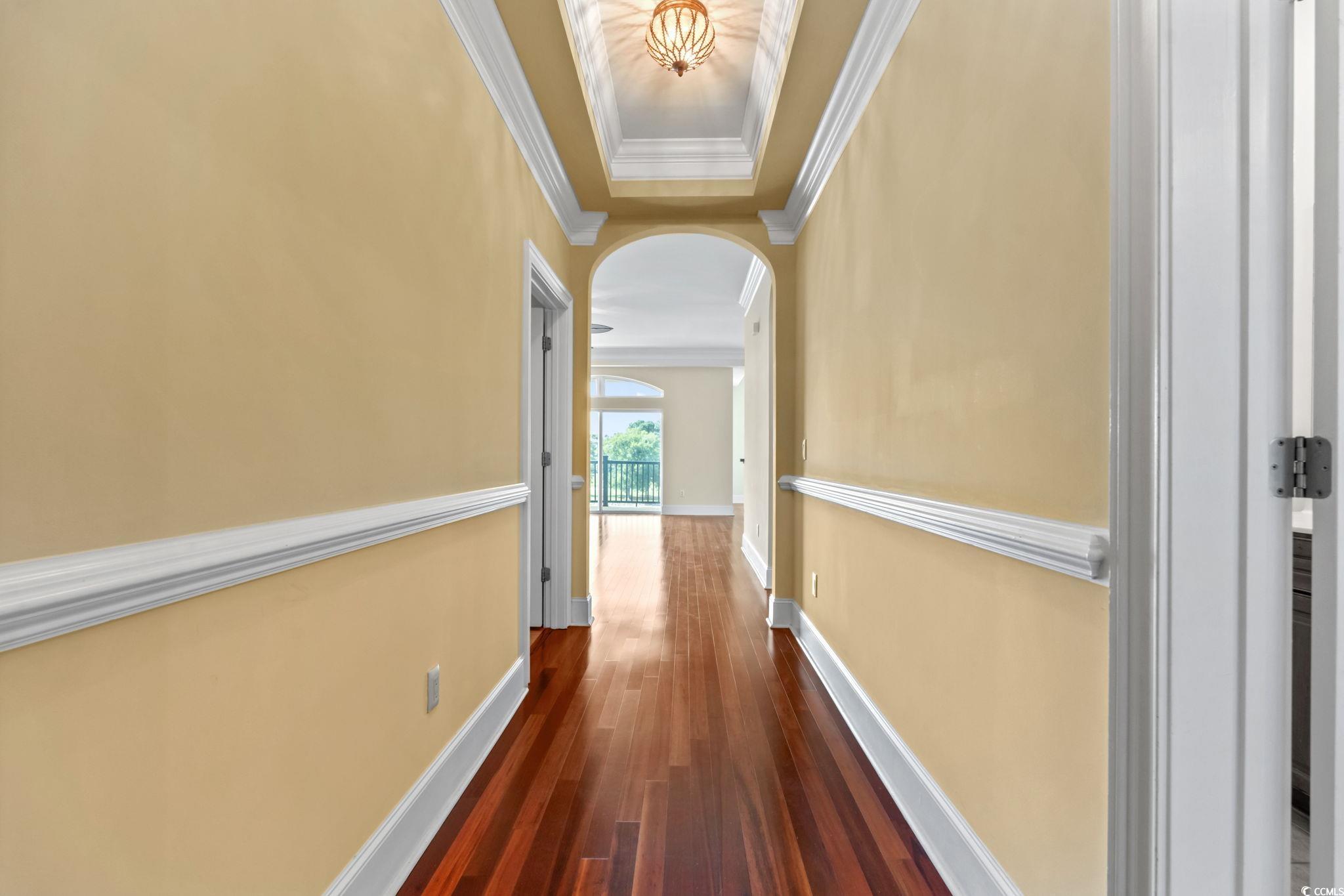 249 Venice Way, Unit 3301 Myrtle Beach, SC 29577 - Photo 3 of 40 Hallway featuring arched walkways, crown molding, dark wood-style flooring, and a tray ceiling