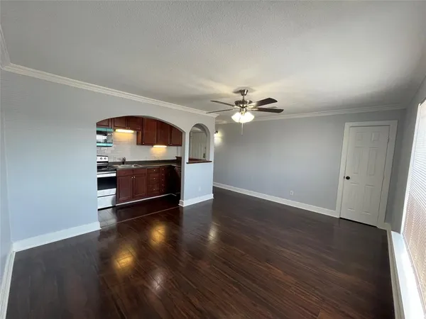an empty room with wooden floor cabinet and windows