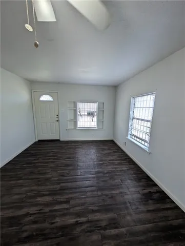 a view of an empty room with wooden floor and a window