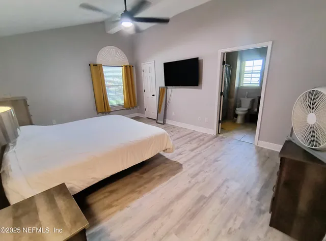 a bedroom with a bed and a flat tv screen on dresser