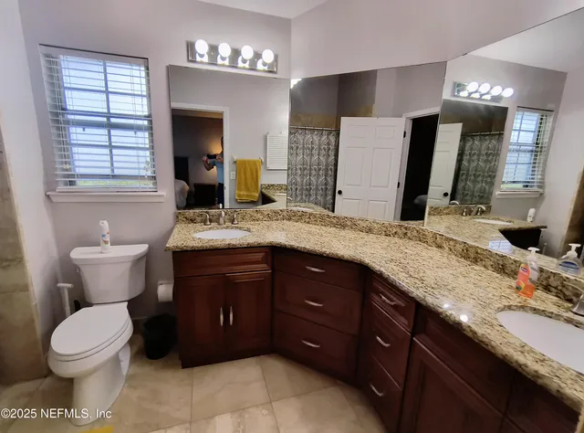 a bathroom with a granite countertop toilet sink and mirror