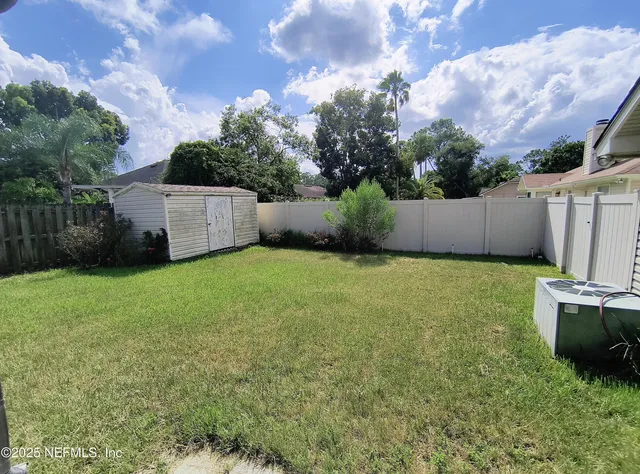 a view of a backyard with potted plants and a large tree