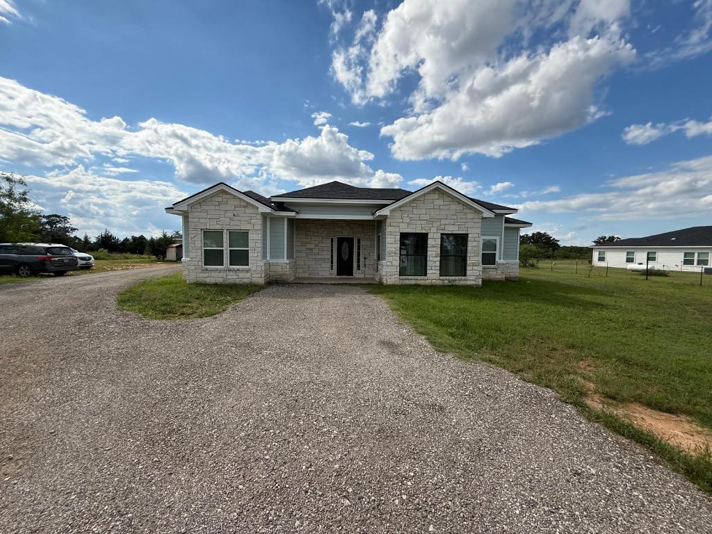 View of front of home featuring stone siding, driveway, and a front yard