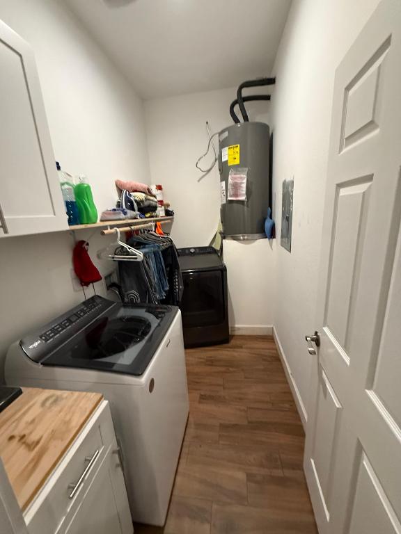 497 Brown Road McDade, TX 78650 - Photo 12 of 22 Clothes washing area featuring cabinet space, water heater, washer and clothes dryer, and wood finished floors
