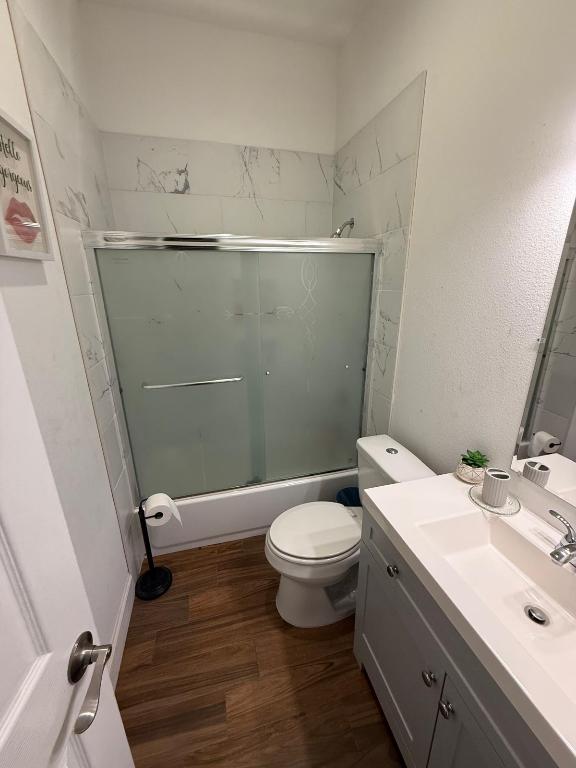 497 Brown Road McDade, TX 78650 - Photo 13 of 22 Bathroom with wood finished floors, vanity, toilet, and combined bath / shower with glass door