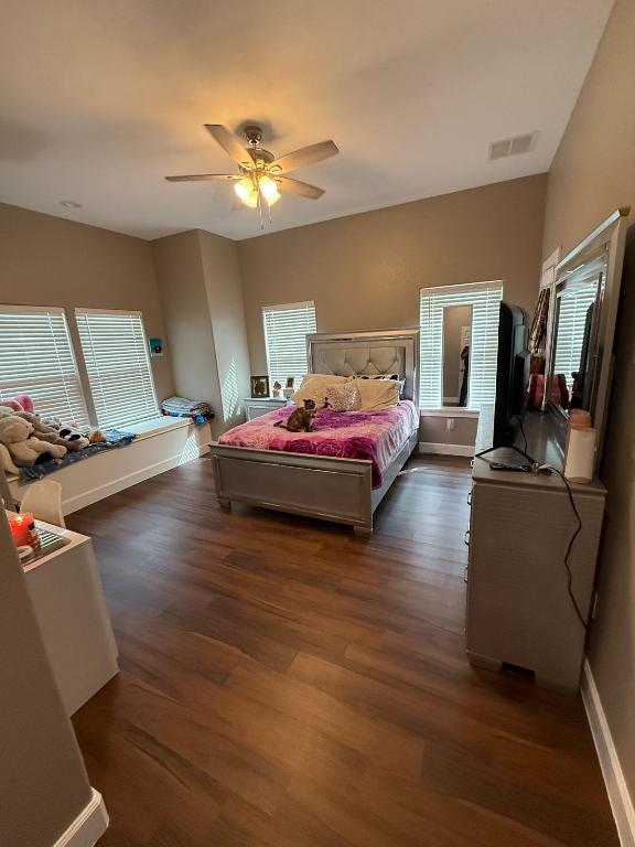 497 Brown Road McDade, TX 78650 - Photo 14 of 22 Bedroom featuring dark wood finished floors, a ceiling fan, multiple windows, and baseboards