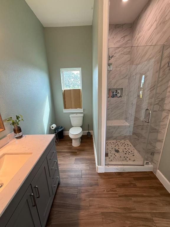 497 Brown Road McDade, TX 78650 - Photo 18 of 22 Bathroom with baseboards, a shower stall, vanity, wood finished floors, and toilet