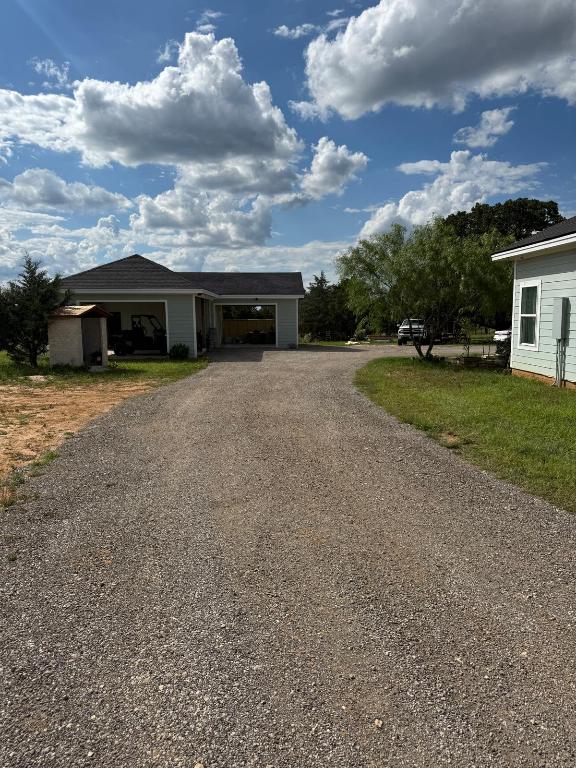 497 Brown Road McDade, TX 78650 - Photo 21 of 22 View of front of home featuring driveway, an outbuilding, an attached carport, and a storage unit