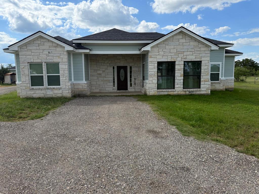 497 Brown Road McDade, TX 78650 - Photo 22 of 22 View of front of property featuring stone siding, a front yard, and a shingled roof