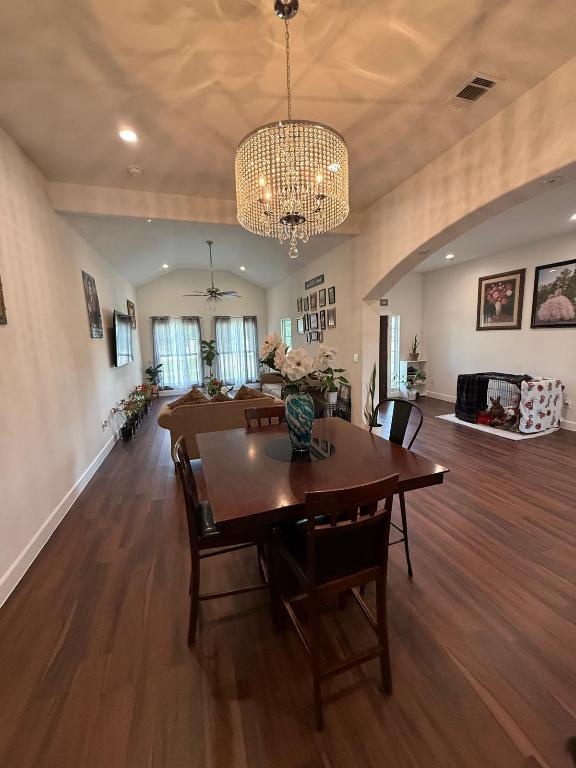 497 Brown Road McDade, TX 78650 - Photo 8 of 22 Dining space featuring lofted ceiling, wood finished floors, arched walkways, a chandelier, and baseboards