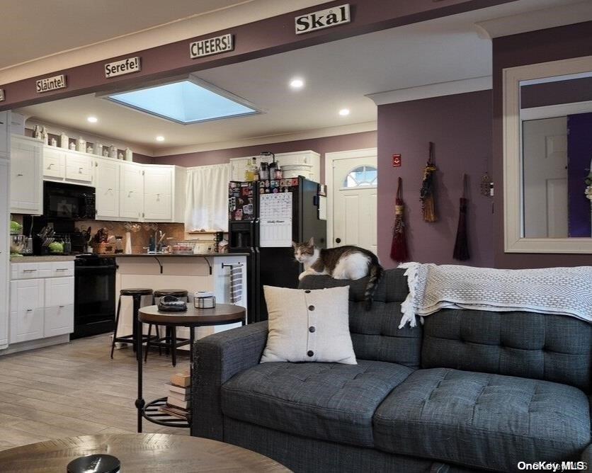 a living room with furniture kitchen view and a wooden floor