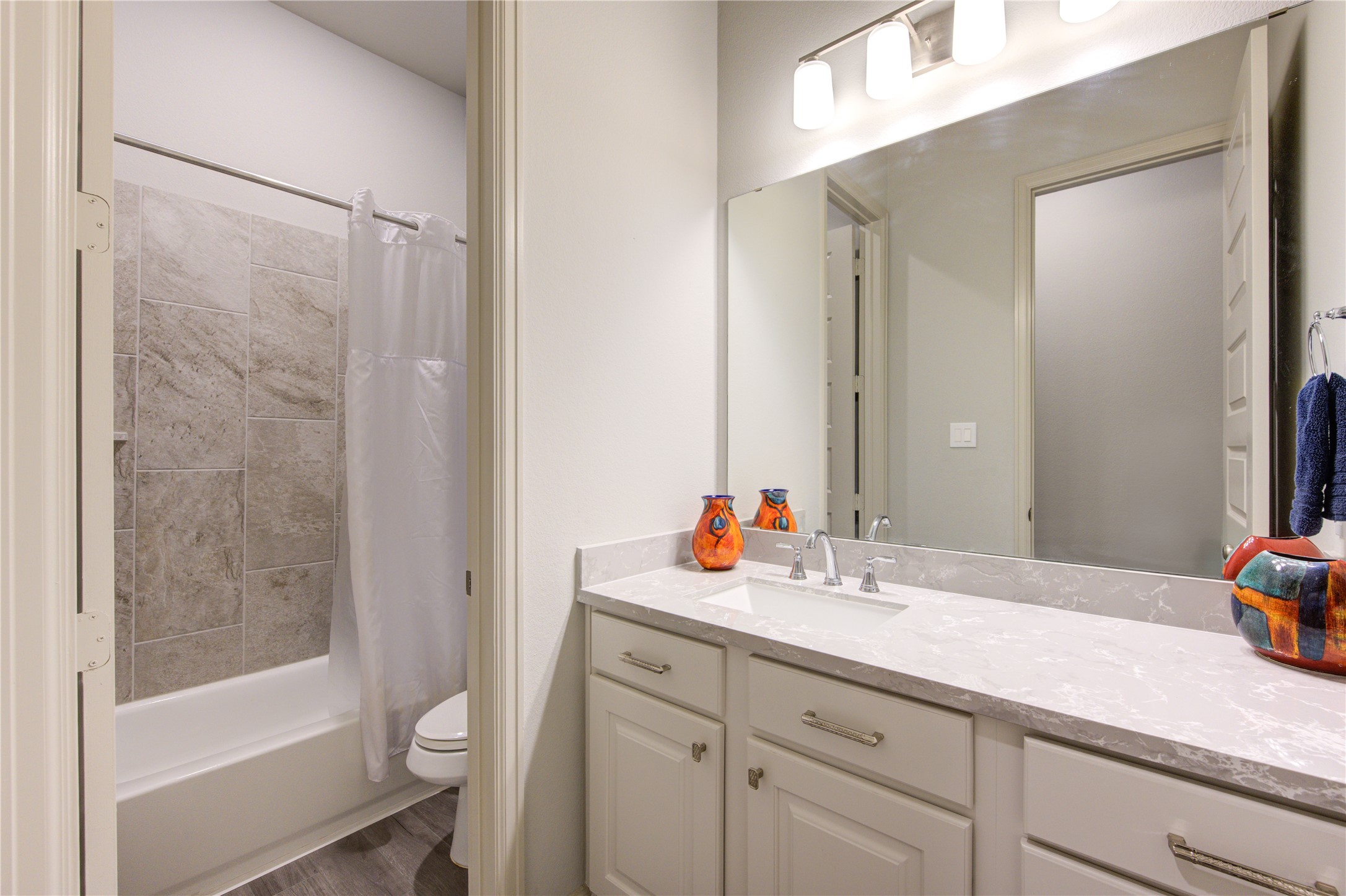 7326 Orangetip Road Katy, TX 77493 - Photo 23 of 43 The third bathroom offers a perfect blend of style and convenience, featuring a Quartz countertop vanity with ample storage and modern brushed nickel fixtures. The soft neutral color palette enhances the bright and airy feel of the space.
A full-size bathtub with a tiled surround provides versatility, ideal for both relaxing soaks and practical everyday use