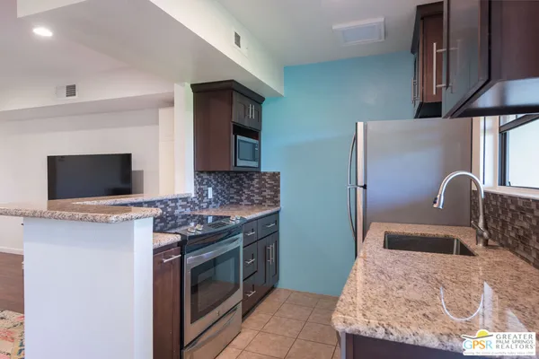 a kitchen with stainless steel appliances granite countertop a stove top oven a sink and a refrigerator