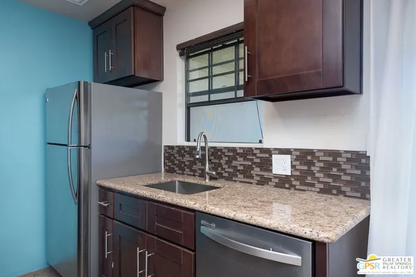 a kitchen with granite countertop a sink cabinets and stainless steel appliances