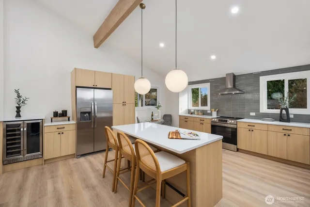 a kitchen with stainless steel appliances a stove a sink a kitchen island with chairs and wooden floor