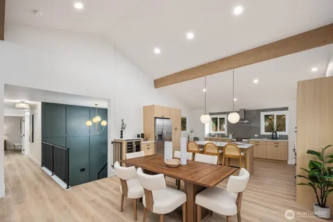 a kitchen with stainless steel appliances kitchen island granite countertop a dining table chairs and a refrigerator