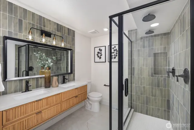 a bathroom with a double vanity sink a toilet a mirror and shower