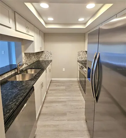 a kitchen with granite countertop a sink a stove and a refrigerator