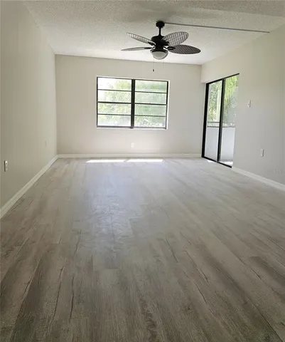 an empty room with windows and ceiling fan