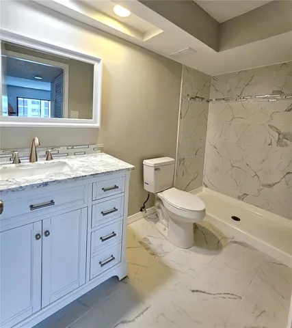 a bathroom with a granite countertop sink toilet and shower