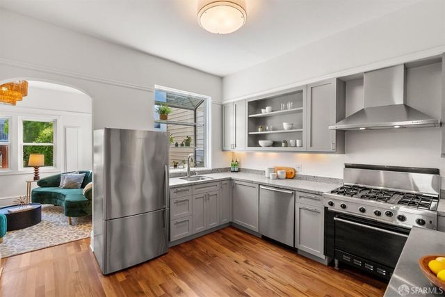 a kitchen with stainless steel appliances granite countertop a stove a refrigerator and a sink with wooden floors