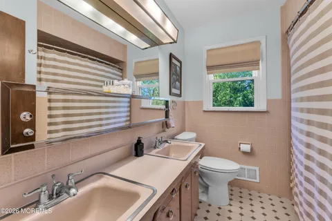 a bathroom with a toilet a sink a mirror and a window