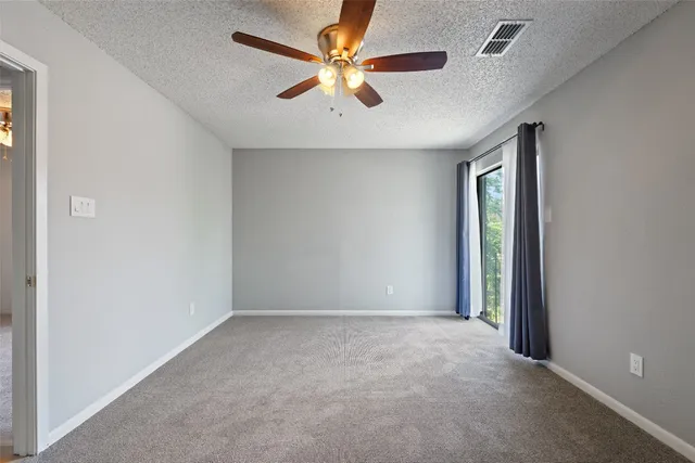 an empty room with windows and fan