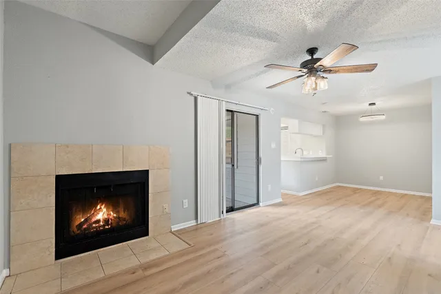 a view of a fireplace with a fireplace a ceiling fan and wooden floor