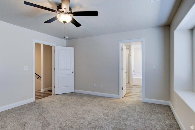 668 East Fiddlers Canyon Road, Unit 24 Cedar City, UT 84721 - Photo 5 of 21 Unfurnished bedroom featuring light carpet, connected bathroom, and a ceiling fan