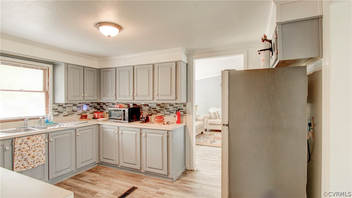 Kitchen featuring white refrigerator, sink, light