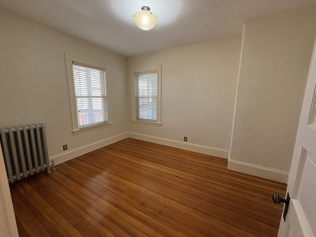 62 Ibbetson Street, Unit 3L Somerville, MA 02143 - Photo 11 of 20 an empty room with wooden floor and windows