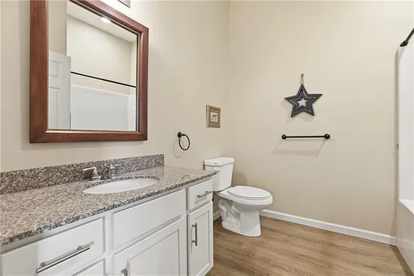 a bathroom with a granite countertop toilet sink and mirror