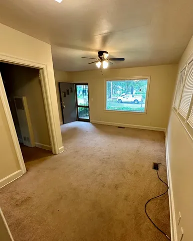 an empty room with chandelier fan and windows