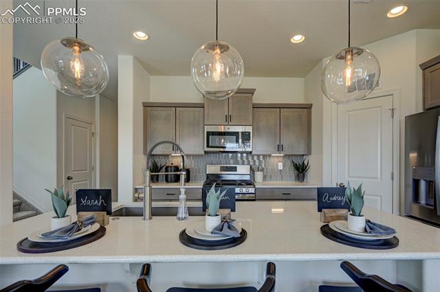 5057 Truscott Road Colorado Springs, CO 80925 - Photo 48 of 48 Kitchen featuring decorative backsplash, appliances with stainless steel finishes, and decorative light fixtures