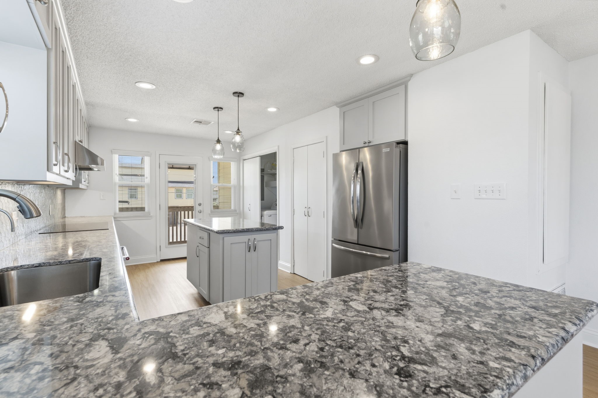 119 Sand Shoals Road Freeport, TX 77541 - Photo 19 of 34 Kitchen prep area — quartz-topped center island, French-door stainless refrigerator, pendant lighting, double pantry storage, and pass-through to the back balcony.