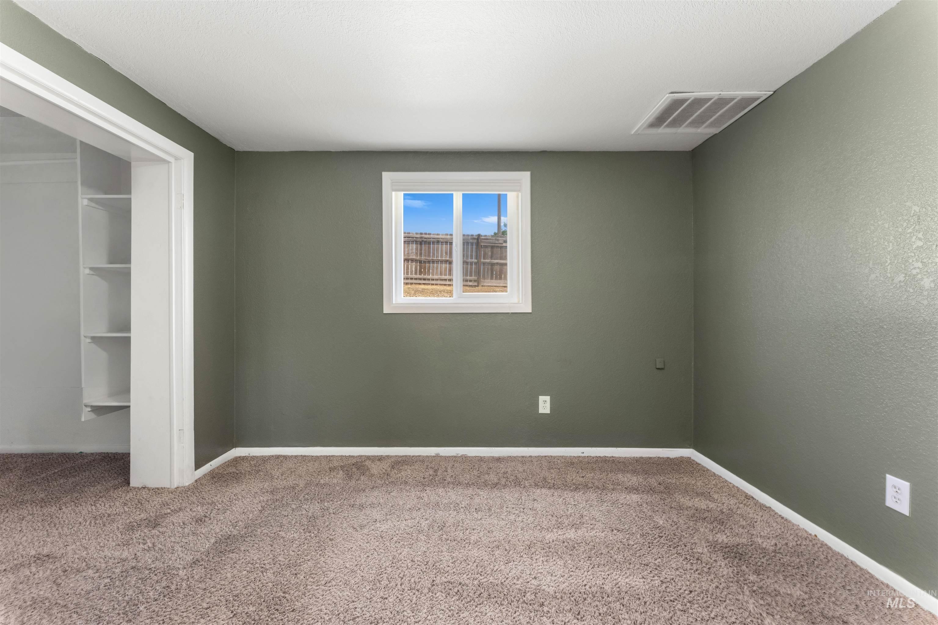 17441 Upper Pleasant Ridge Road Caldwell, ID 83607 - Photo 24 of 40 Room featuring wall-to-wall carpeting, painted walls, white trim, and a window with a backyard view