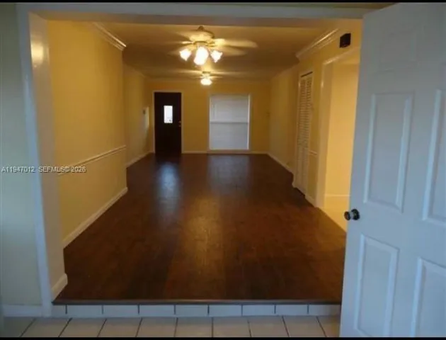 a view of a hallway with wooden floor and a bathroom