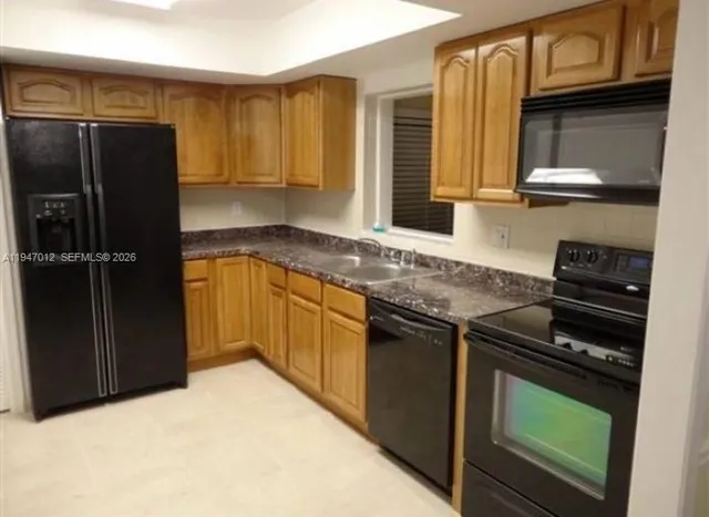 a kitchen with granite countertop a refrigerator and a sink