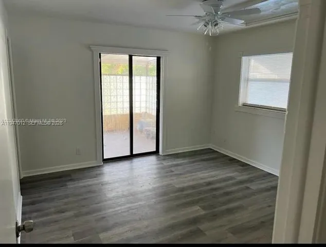 an empty room with wooden floor closet and windows