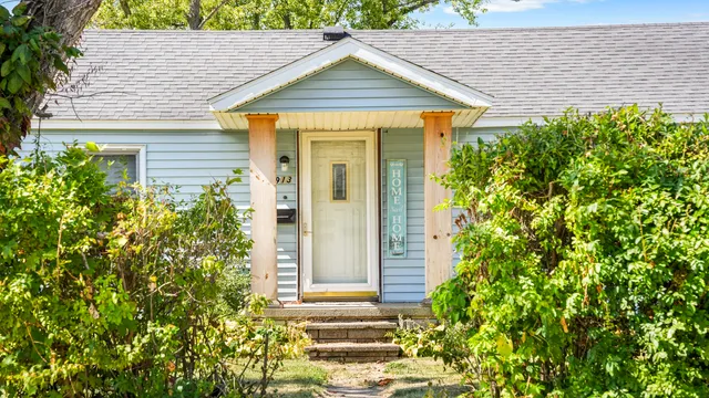 a view of a house with potted plants and a table and chair
