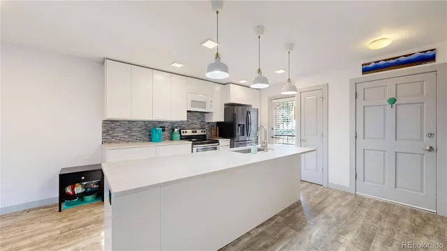 a large white kitchen with a large island oven a sink stainless steel appliances and cabinets