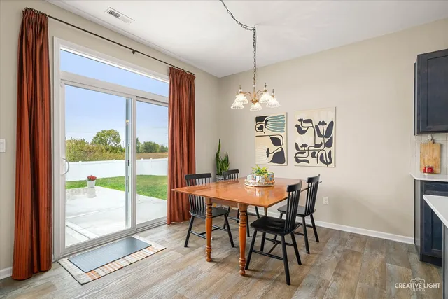 a kitchen with granite countertop a stove top oven a sink dishwasher a dining table and chairs with wooden floor