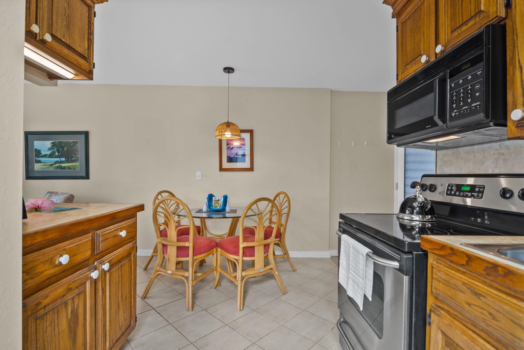4057 Lower Honoapiilani Road, Unit 116 Lahaina, HI 96761 - Photo 22 of 38 a kitchen with stainless steel appliances a stove a sink cabinets and a dining table